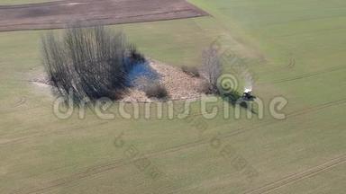 农用拖拉机在春麦田、空中撒肥